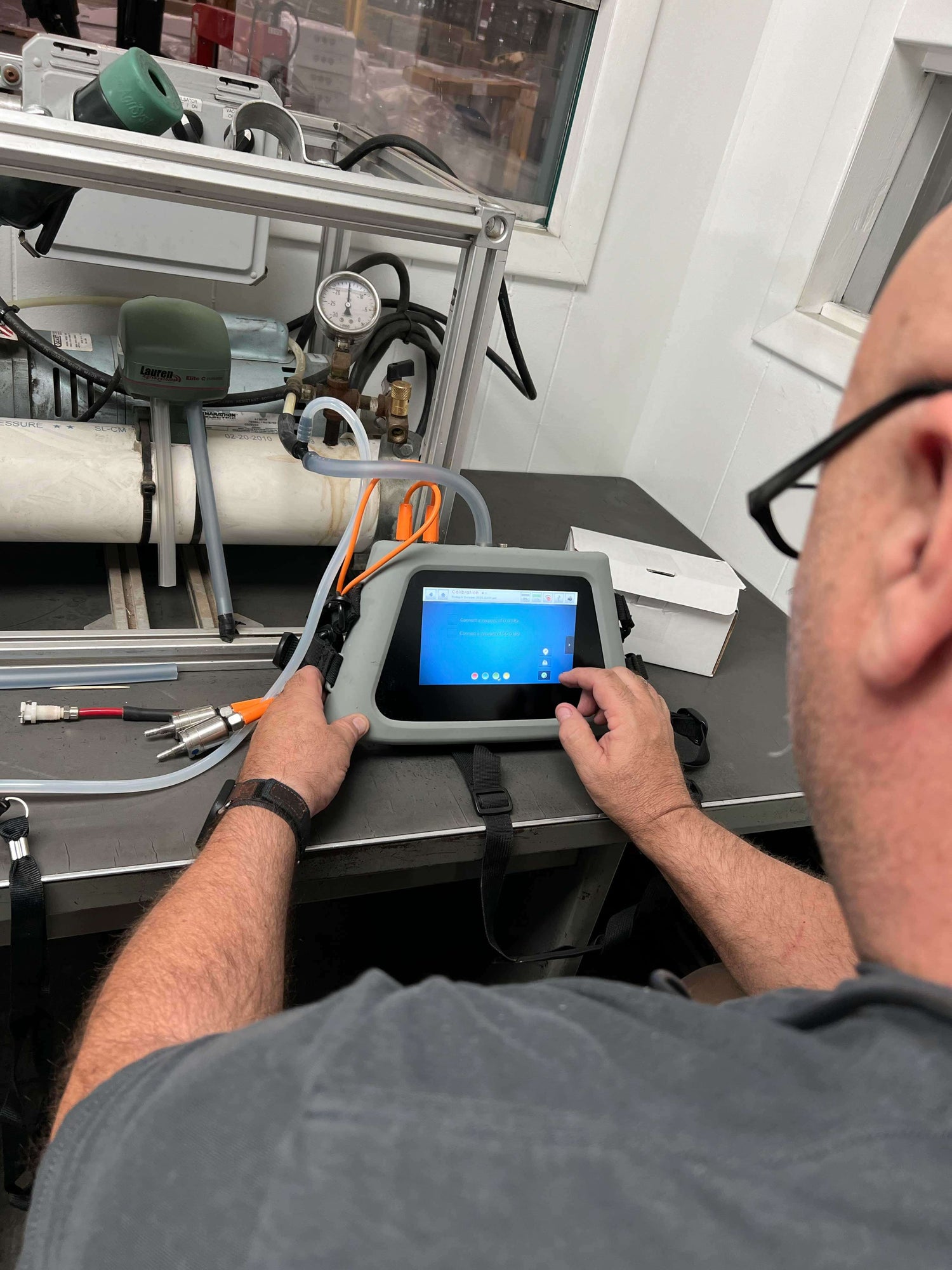 Technician using PT-6 Basic Kit touchscreen for dairy equipment testing in a lab setting.